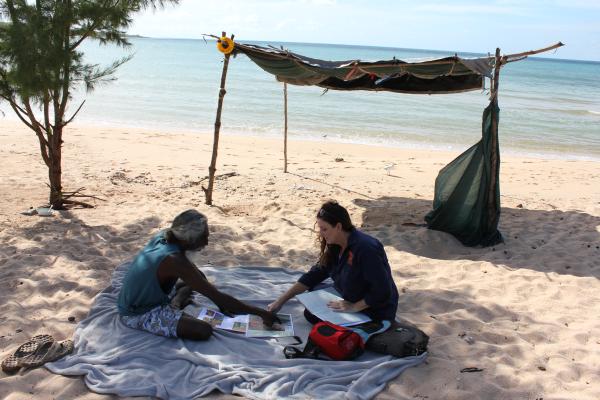 Two people reviewing a map on a beach