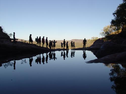 Silhouetted people standing on the edge of the Gunlom Falls top pool