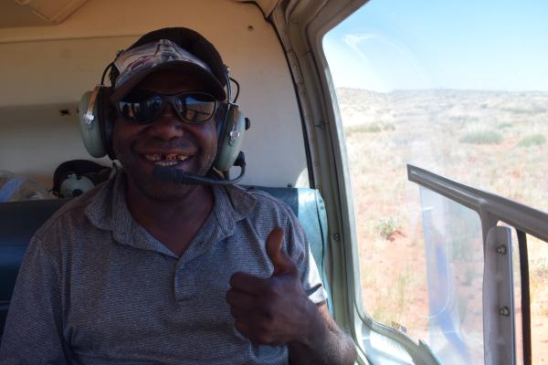 Aboriginal custodian in a helicopter giving a thumbs up